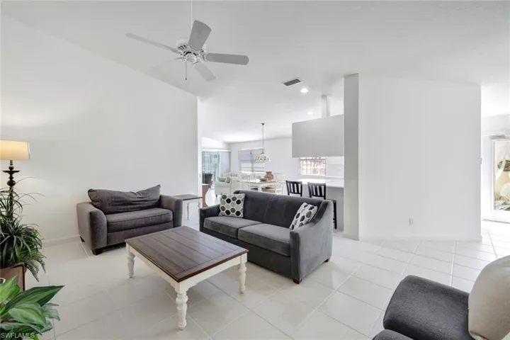Living room featuring a ceiling fan, light tile patterned flooring, visible vents, and baseboards