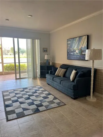 Living room with light tile patterned floors, crown molding, and wainscoting