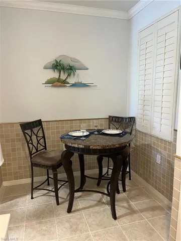 Dining space featuring wainscoting, crown molding, tile walls, and light tile patterned floors