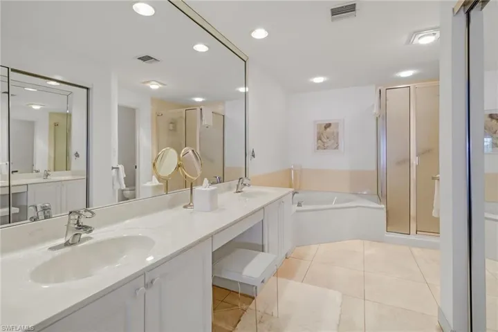 Bathroom featuring a stall shower, double vanity, a garden tub, light tile patterned floors, and recessed lighting