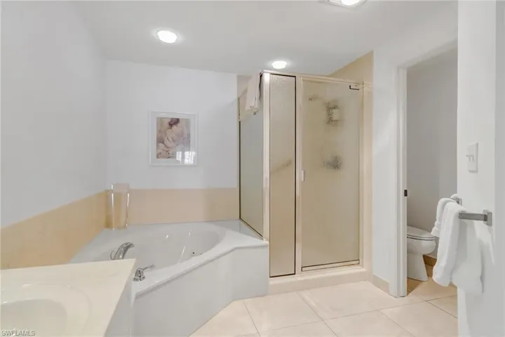 Bathroom featuring a shower stall, vanity, light tile patterned flooring, and a garden tub