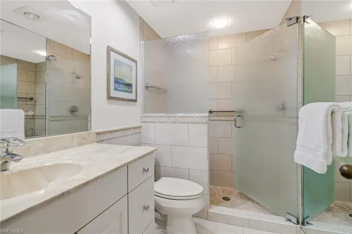 Full bath featuring vanity, tile walls, and a shower stall