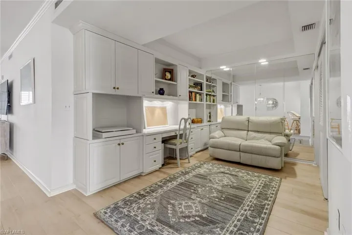 Office space with light wood finished floors, built in study area, and ornamental molding
