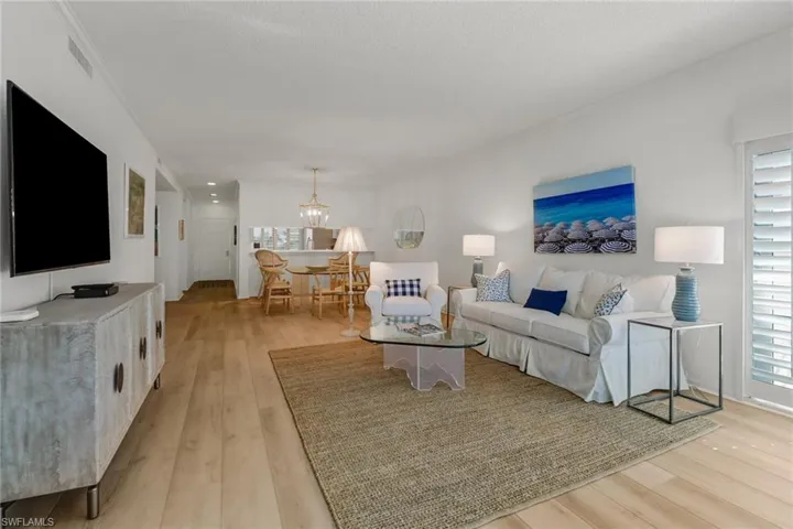Living room featuring light wood finished floors, a chandelier, and a textured ceiling