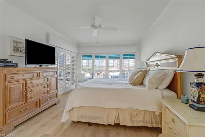 Bedroom with access to outside, ornamental molding, light wood-type flooring, and a ceiling fan