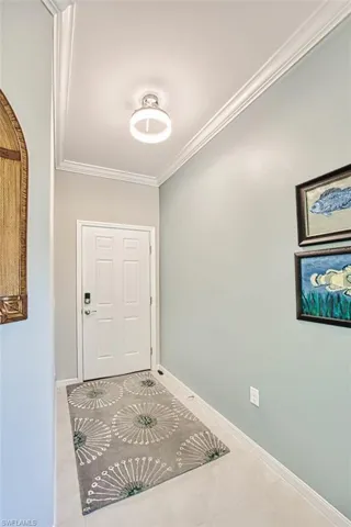 Entryway with tile patterned flooring, crown molding, and baseboards