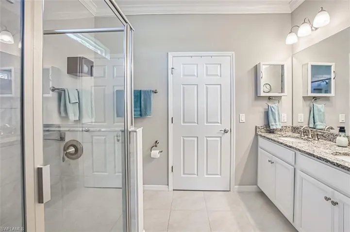 Bathroom featuring ornamental molding and a shower stall