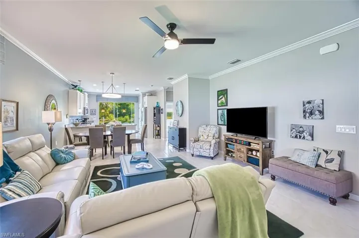 Living area featuring crown molding, light tile patterned floors, and ceiling fan