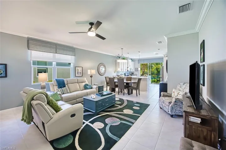 Living room with crown molding, light tile patterned floors, a ceiling fan