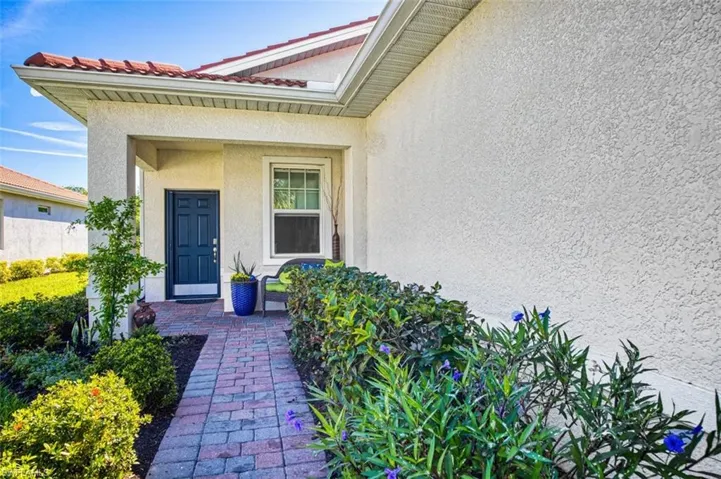View of exterior entry lined with mature landscaping