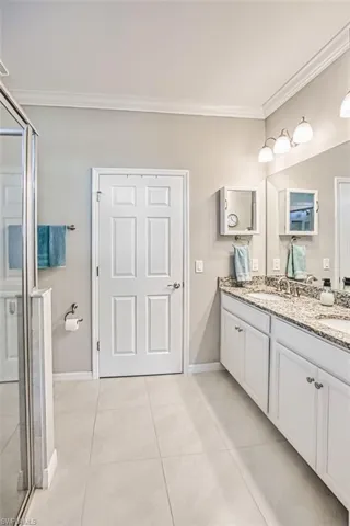 Full bath with crown molding, tile patterned floors, a shower stall, and a sink