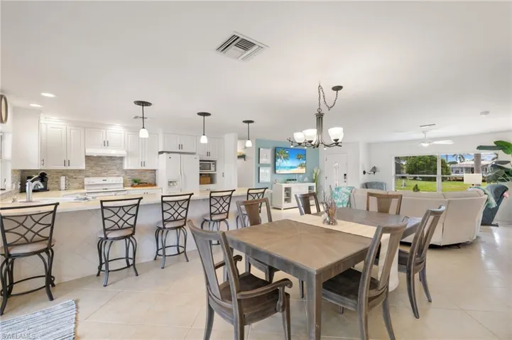 Dining area with a chandelier, a ceiling fan, light tile patterned flooring, and recessed lighting