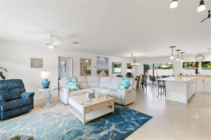 Living room with light tile patterned floors, a chandelier, and ceiling fan