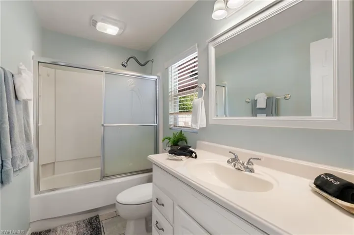 Full bath with enclosed tub / shower combo, vanity, and light tile patterned floors