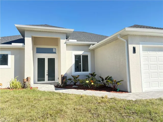 Doorway to property with a lawn, a garage, and french doors