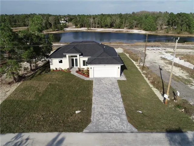 View of front of property with a front lawn, a water view, and a garage