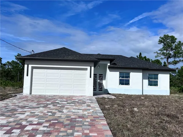 View of front of house with decorative driveway, stucco siding, a garage, a shingled roof, and french doors