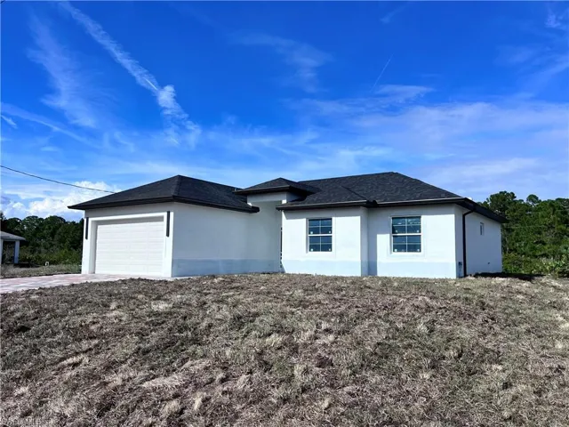 View of front of property featuring an attached garage, stucco siding, driveway, and roof with shingles