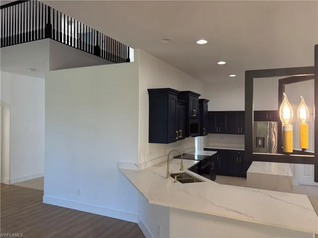 Kitchen featuring stainless steel appliances, light stone counters, a peninsula, recessed lighting, and light wood-type flooring