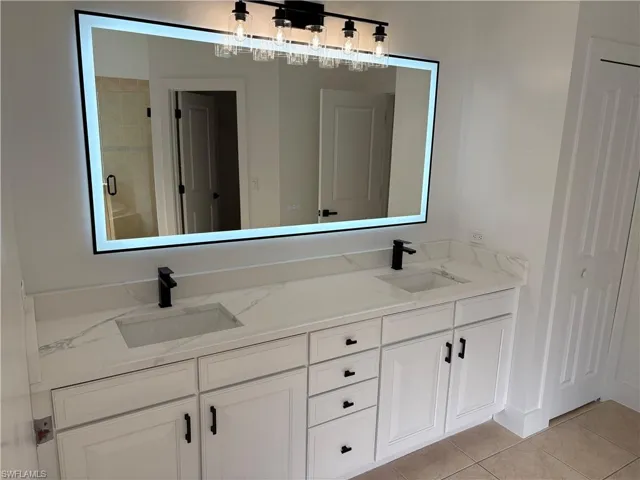 Bathroom with double vanity, light tile patterned floors, a closet, and a shower stall