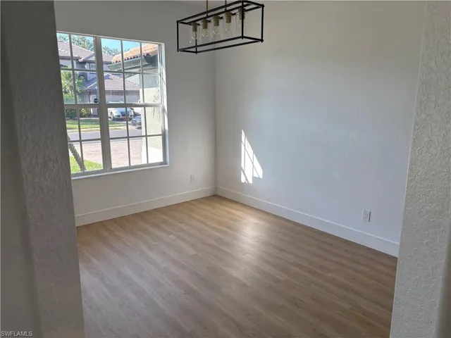 Spare room with a textured wall, a chandelier, and light wood-type flooring