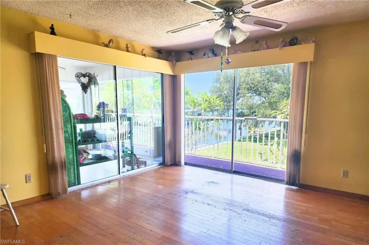 Spare room featuring healthy amount of natural light, a water view, a ceiling fan, light wood-type flooring, and a textured ceiling