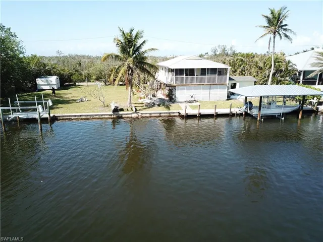 Dock area featuring boat lift, a water view, and a yard