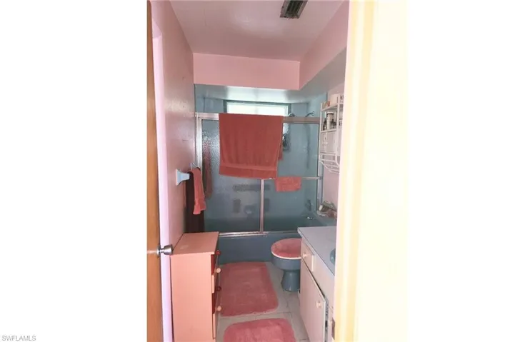 Bathroom featuring shower / bath combination with glass door, vanity, and light tile patterned flooring