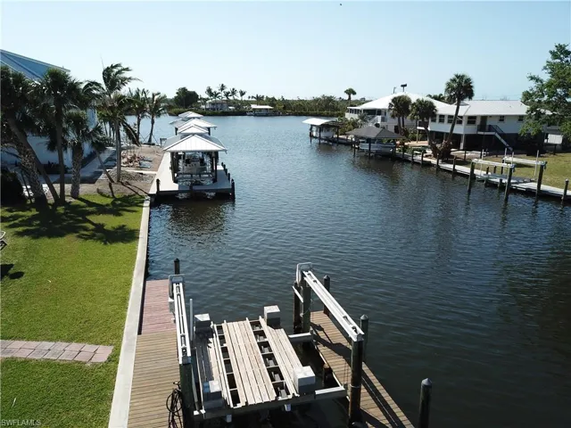 View of dock featuring boat lift, a water view, and a yard
