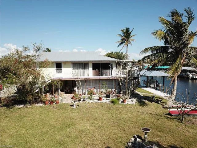 Rear view of property featuring a water view, stairway, a yard, and metal roof