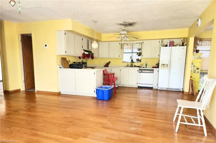 Kitchen featuring white appliances, a textured ceiling, light wood-type flooring, a ceiling fan, and white cabinetry