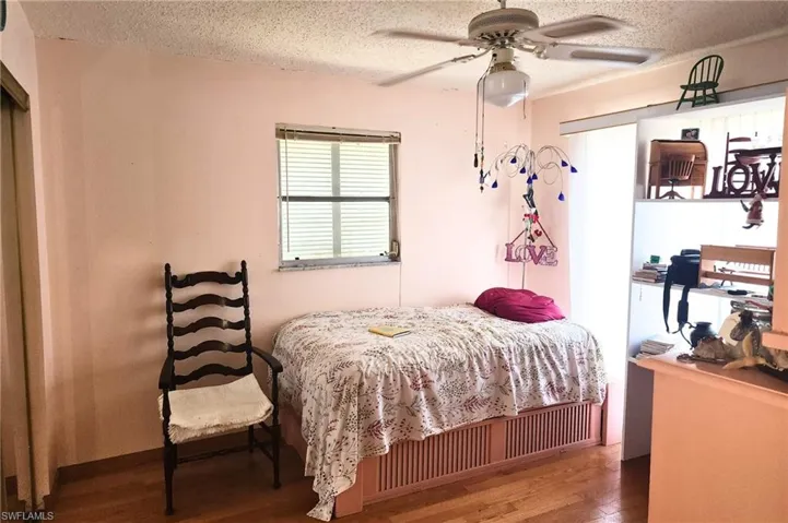 Bedroom with a textured ceiling, wood finished floors, and a ceiling fan