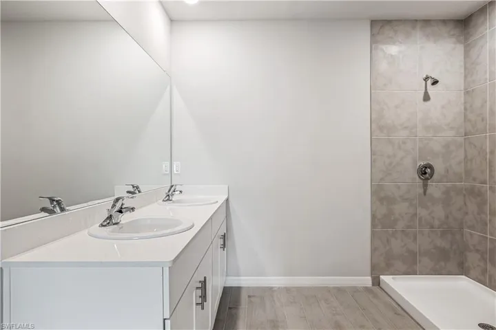 Bathroom featuring vanity, wood-type flooring, and tiled shower