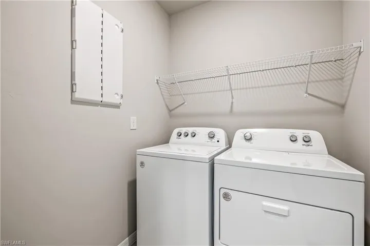 Laundry area featuring electric panel and washing machine and clothes dryer
