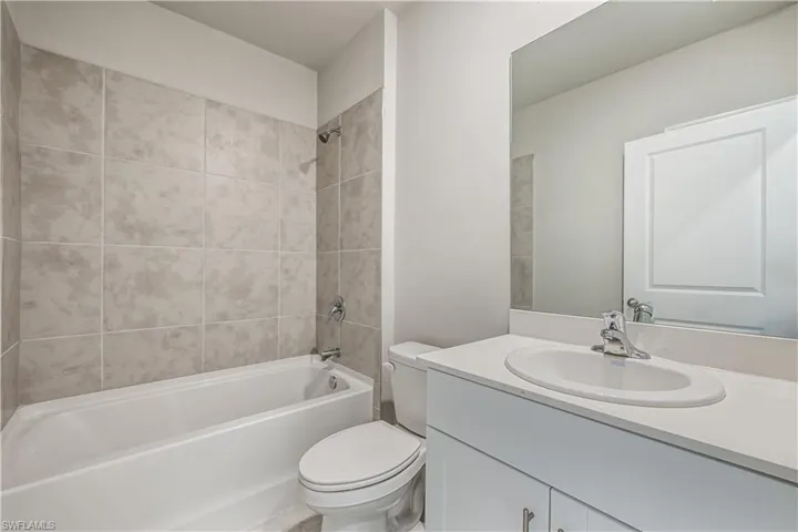 Full bathroom featuring tiled shower / bath, vanity, and toilet