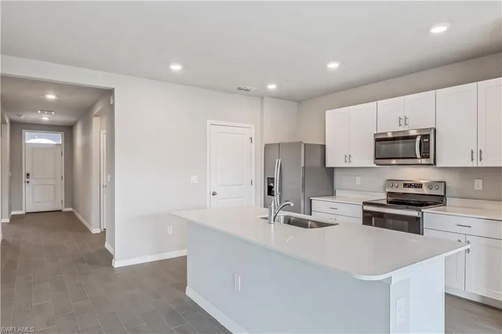 Kitchen featuring an island with sink, sink, white cabinets, appliances with stainless steel finishes, and light hardwood / wood-style floors