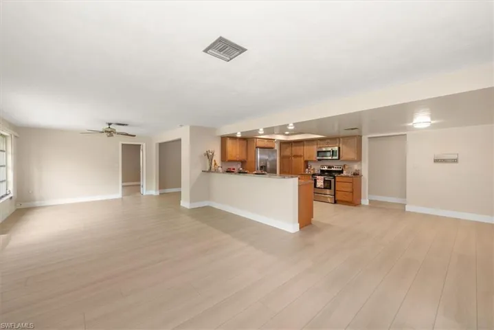 Open-concept living area featuring light wood-finish flooring, a ceiling fan, and recessed lighting