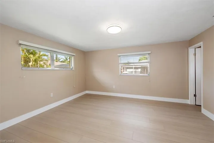Spacious room featuring light wood-finish flooring, neutral wall tones, and white trim