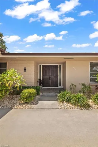 Mid-century modern exterior featuring a flat roofline, double entry doors, brick facade detailing, and a concrete driveway