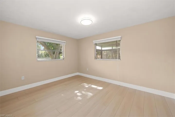 Interior room featuring light-toned walls, wood-finish flooring, and two windows with blinds