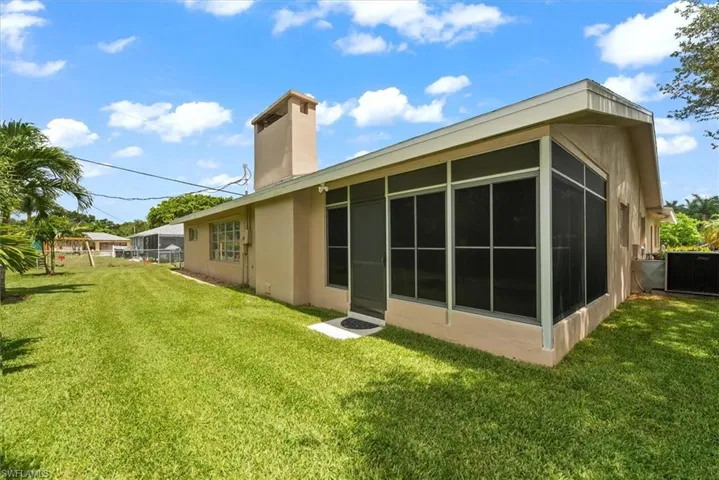 Expansive green lawn surrounds the stucco exterior, featuring a screened porch addition