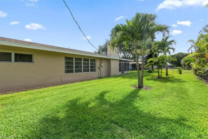 Expansive grassy yard featuring multiple established palm trees