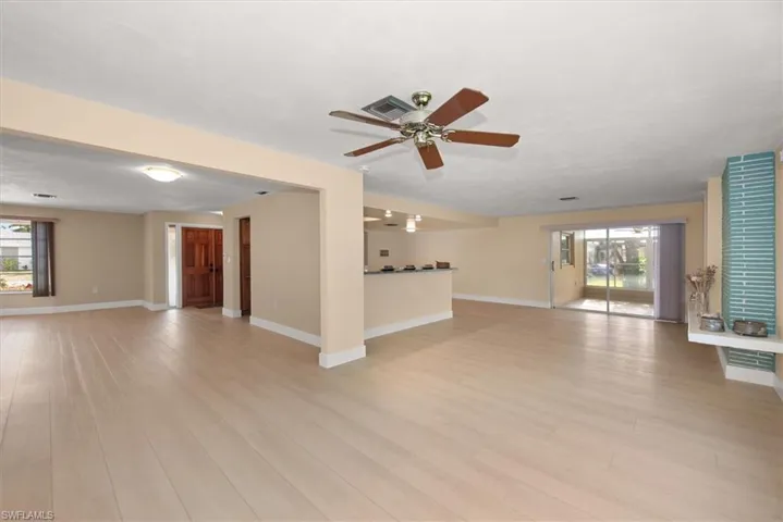 Spacious living area featuring light wood-finish flooring, a contemporary ceiling fan, and sliding glass doors to the exterior