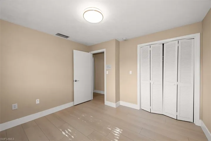 Room featuring light-toned wood-finish flooring, neutral wall paint, and white baseboards