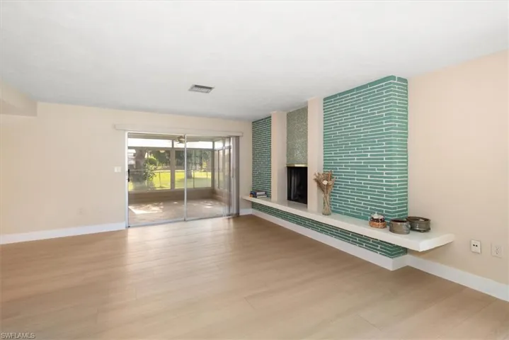 Spacious interior with light wood-finish flooring, a contemporary fireplace featuring teal horizontal tile, and a floating white mantel