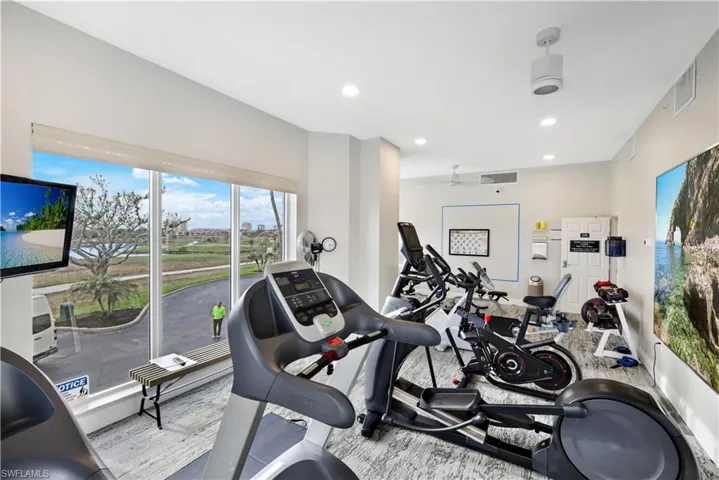Community Exercise area with ceiling fan and light hardwood / wood-style flooring