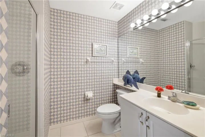 Bathroom featuring toilet, vanity, tile patterned floors, and walk in shower