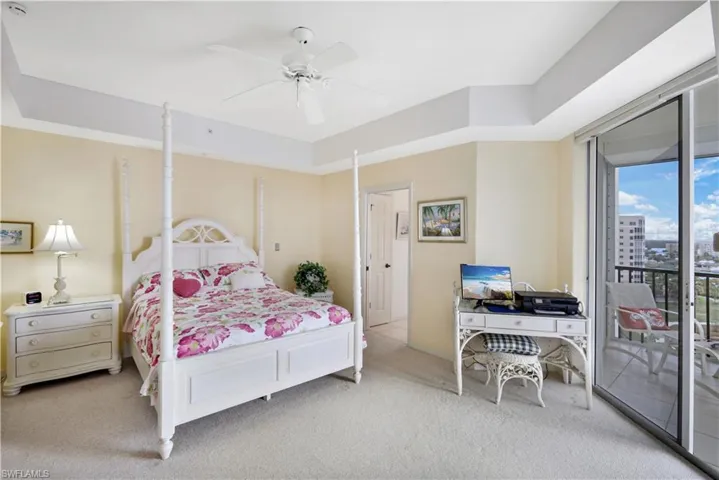 Bedroom with a raised ceiling, access to exterior, ceiling fan, and light colored carpet