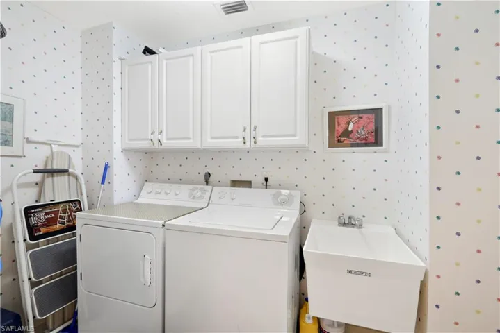Laundry area featuring washing machine and clothes dryer, sink, and cabinets