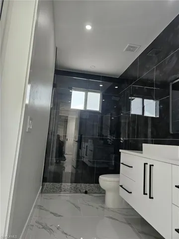 Full bathroom with recessed lighting, a shower stall, visible vents, toilet, and vanity